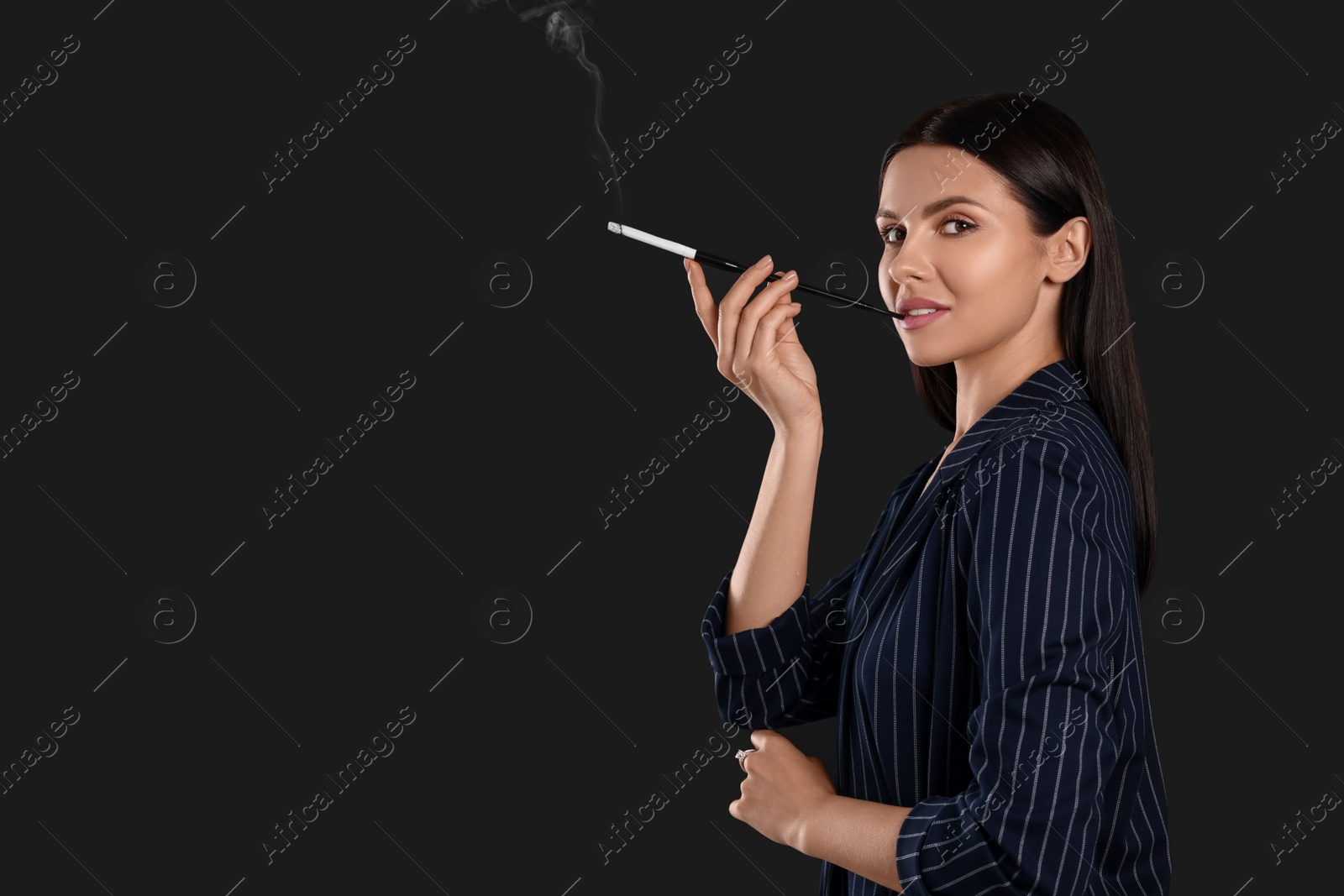 Photo of Woman using long cigarette holder for smoking on black background, space for text