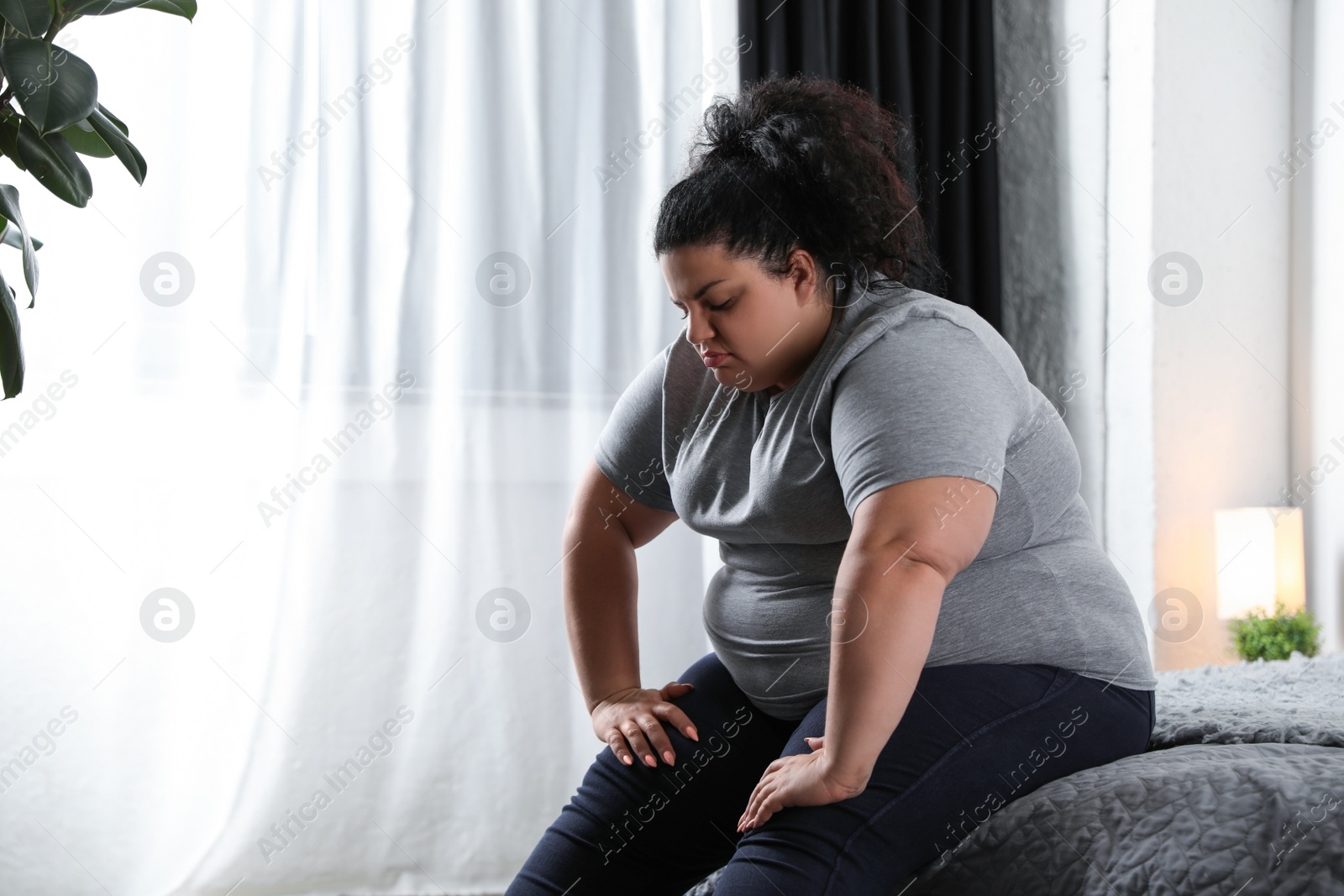 Photo of Depressed overweight woman on bed at home