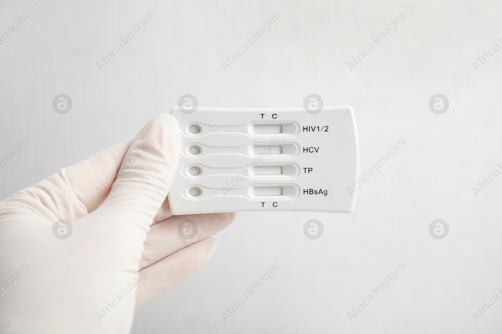 Photo of Doctor in gloves holding disposable express test for hepatitis on white background, closeup