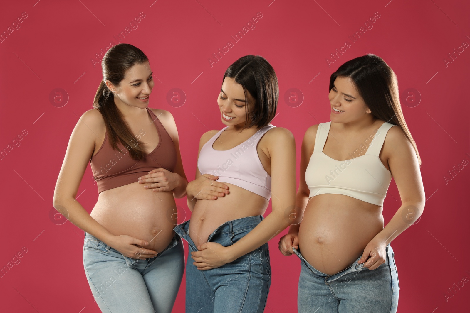 Photo of Happy young pregnant women on red background