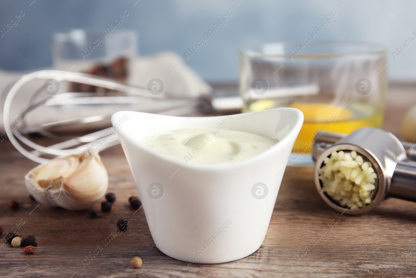 Photo of Composition with bowl of garlic sauce on wooden table