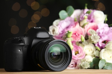 Modern camera and bouquet on wooden table, space for text. International Photographer's day