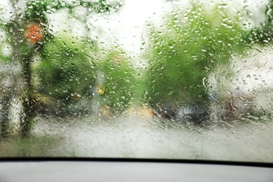 Blurred view of road through wet car window. Rainy weather