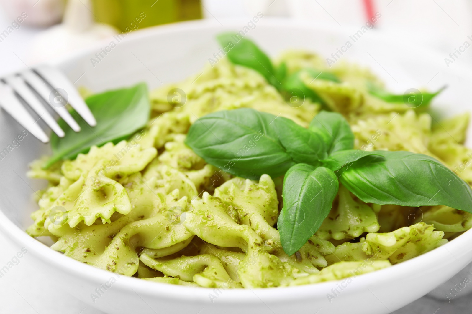 Photo of Delicious pasta with pesto sauce and basil in bowl, closeup