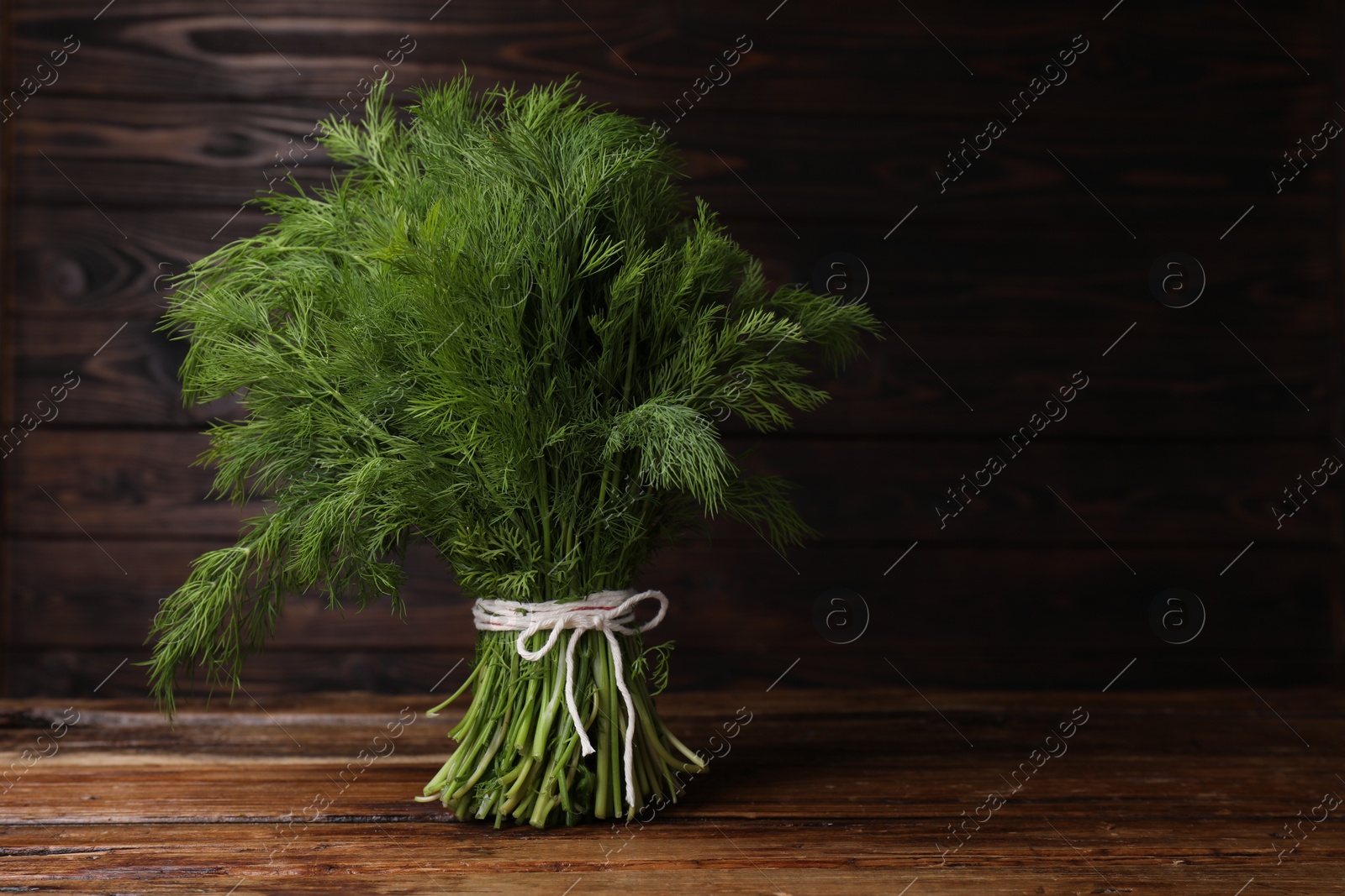 Photo of Bunch of fresh green dill on wooden table, space for text