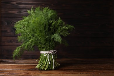 Photo of Bunch of fresh green dill on wooden table, space for text