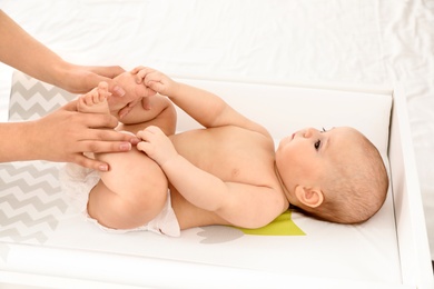 Photo of Mother and her cute child on changing table. Baby massage and exercises