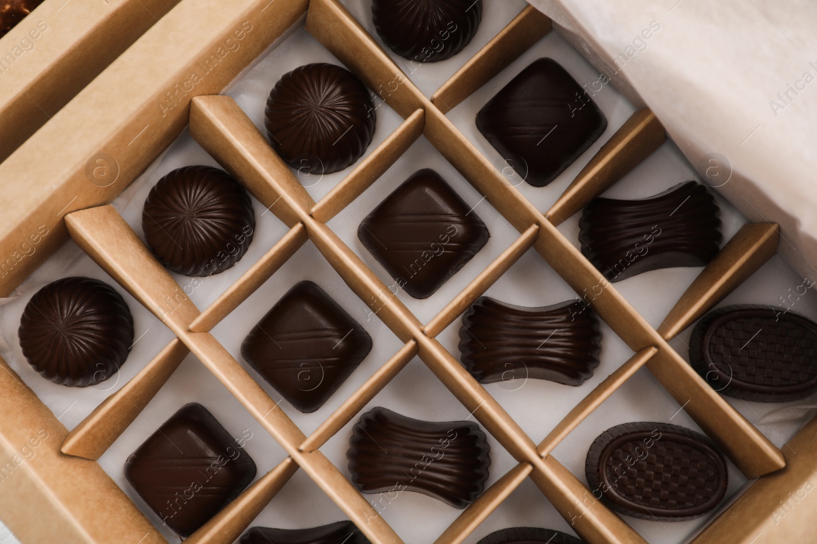 Photo of Many delicious chocolate candies in box, top view