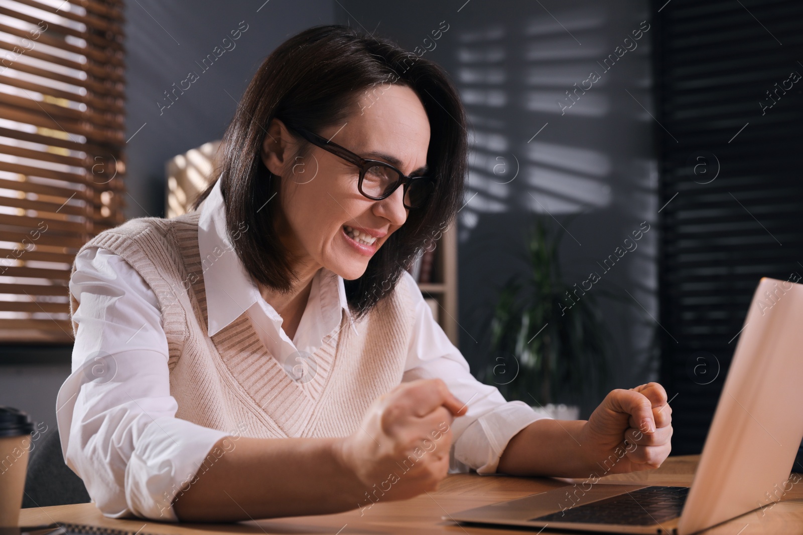 Photo of Emotional businesswoman working on laptop in office. Online hate concept