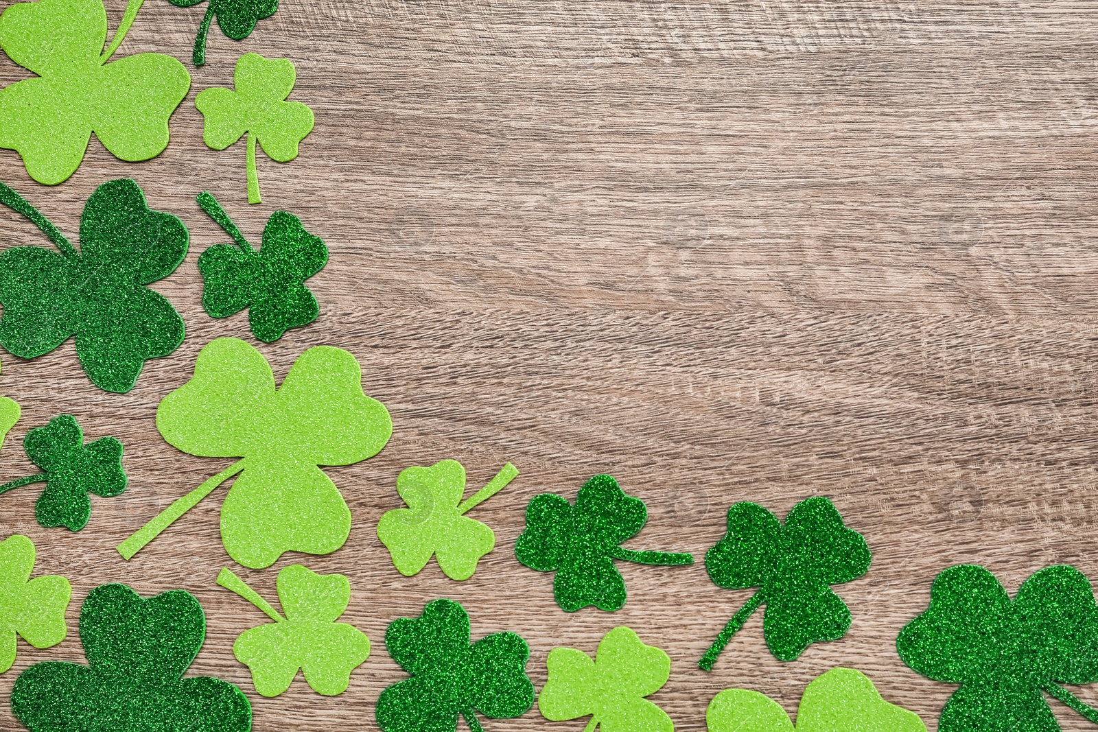 Photo of Decorative clover leaves on grey wooden table, flat lay with space for text. Saint Patrick's Day celebration