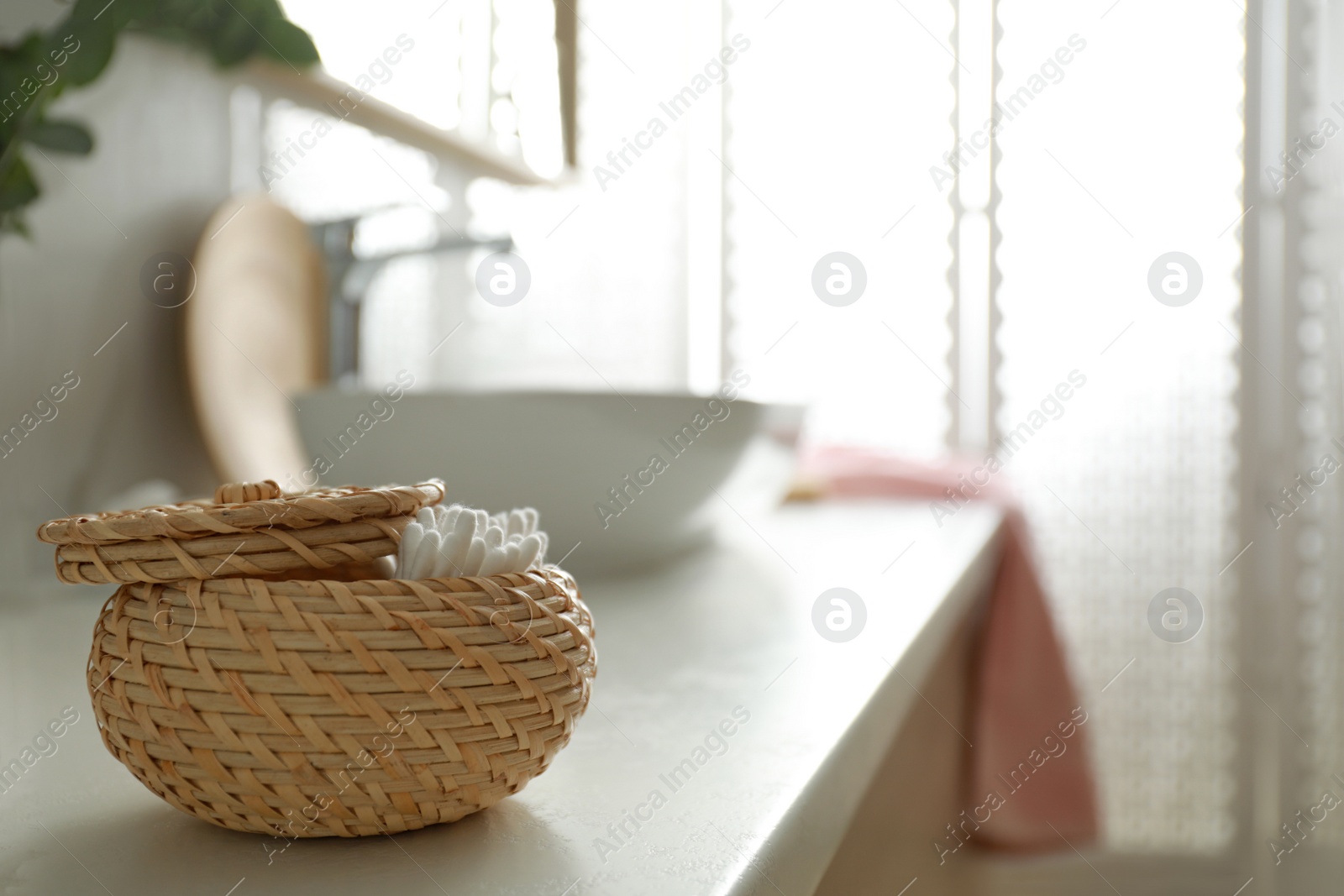 Photo of Basket with cotton buds in modern bathroom interior