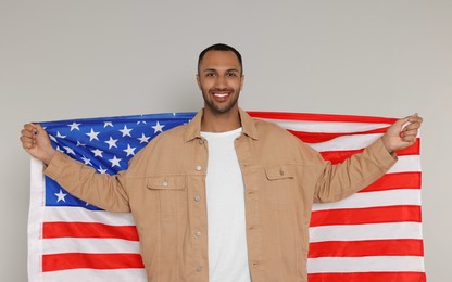 Photo of 4th of July - Independence Day of USA. Happy man with American flag on light grey background