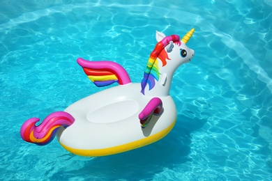 Photo of Funny inflatable unicorn ring floating in swimming pool on sunny day