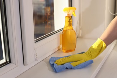 Photo of Woman cleaning window sill with rag at home, closeup