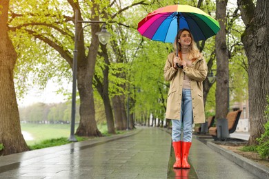 Photo of Young woman with umbrella walking in park on spring day