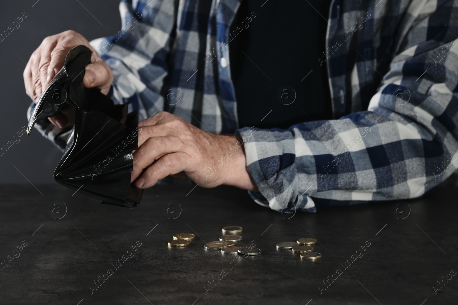 Photo of Poor elderly man counting coins at table, focus on hands