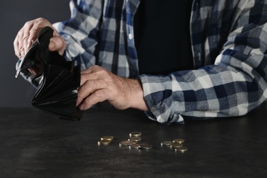 Photo of Poor elderly man counting coins at table, focus on hands