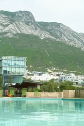 Outdoor swimming pool, hotel and beautiful mountain on background