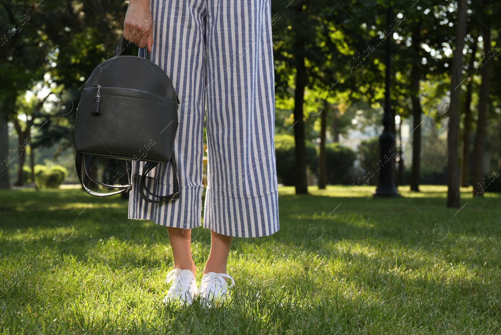 Photo of Young woman with stylish backpack in park, closeup