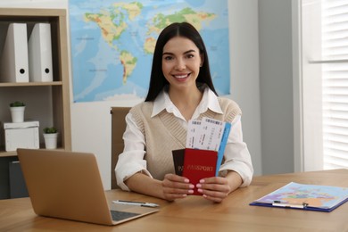 Travel agent with tickets and passports at table in office