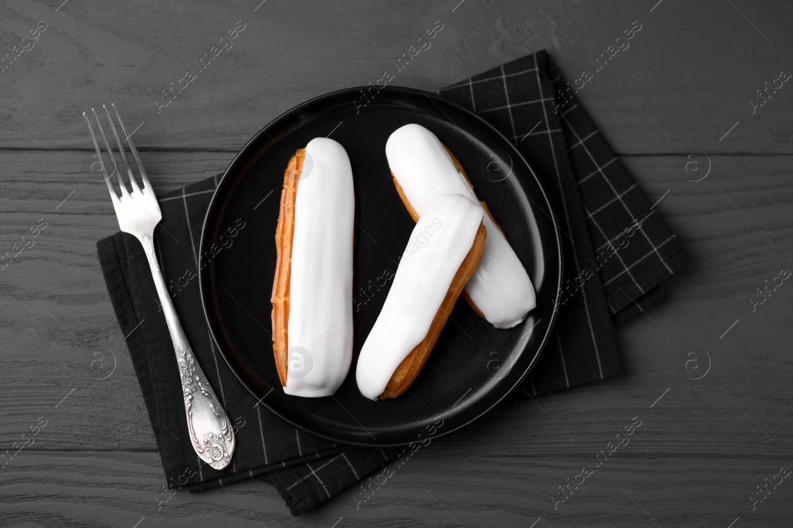 Photo of Delicious eclairs covered with glaze on grey wooden table, top view