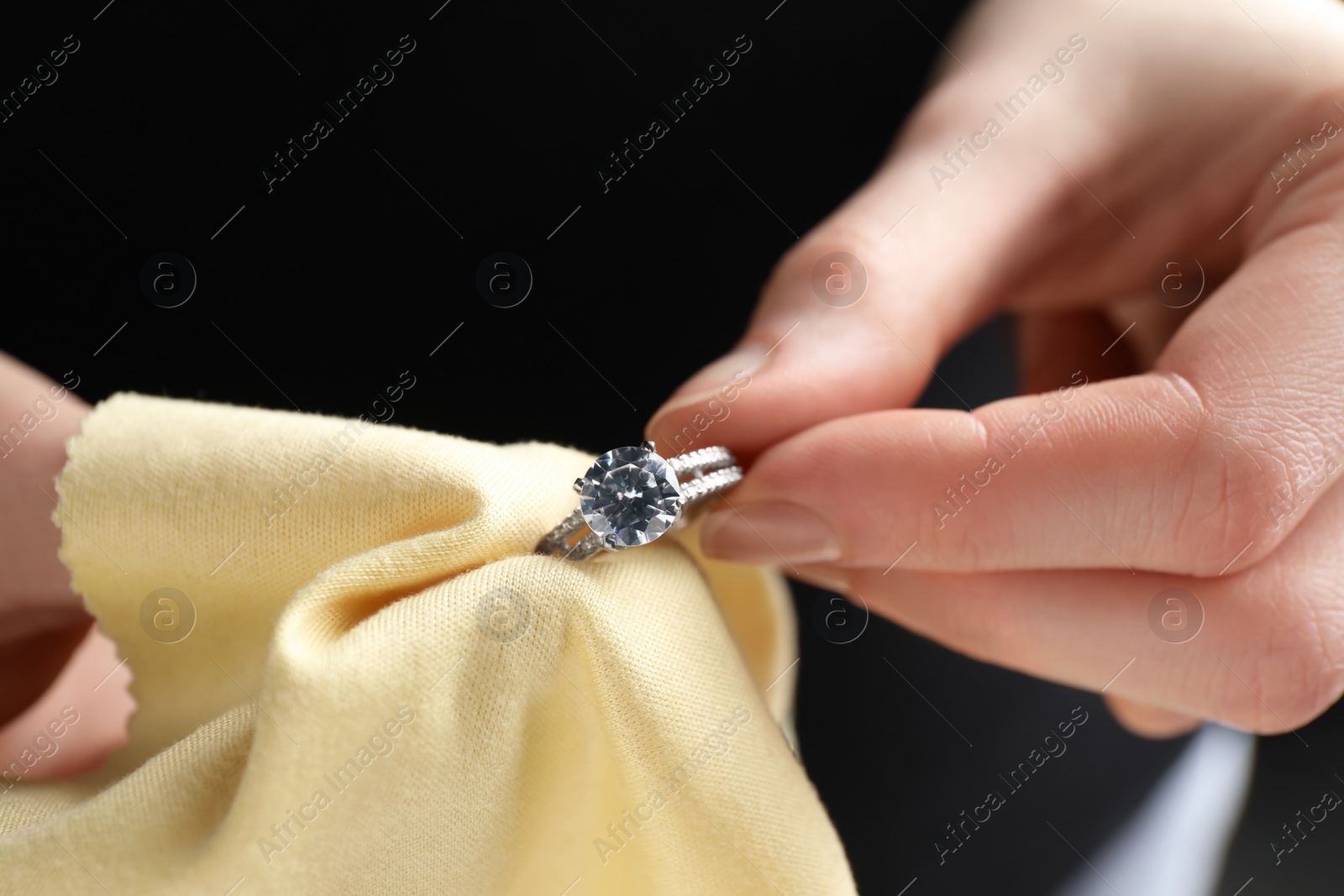 Photo of Jeweler cleaning diamond ring with microfiber cloth, closeup