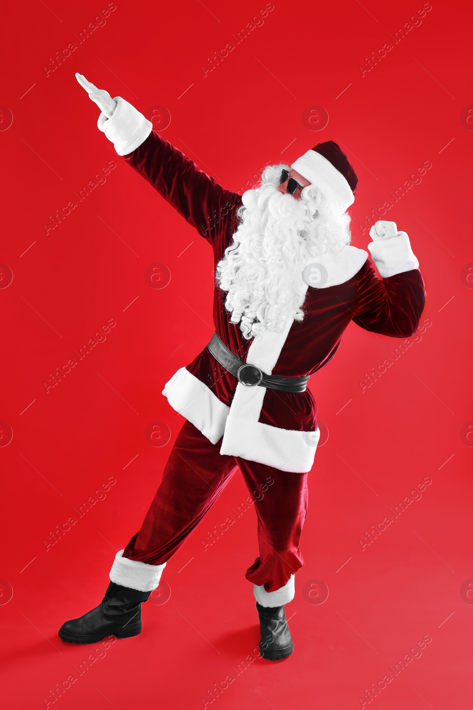 Photo of Full length portrait of Santa Claus with sunglasses on red background