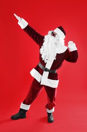 Full length portrait of Santa Claus with sunglasses on red background