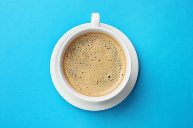 Photo of Aromatic coffee in cup on light blue background, top view