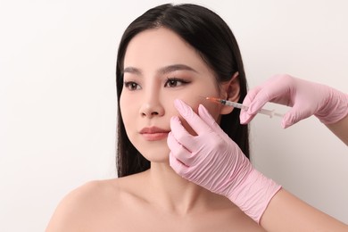 Woman getting facial injection on white background