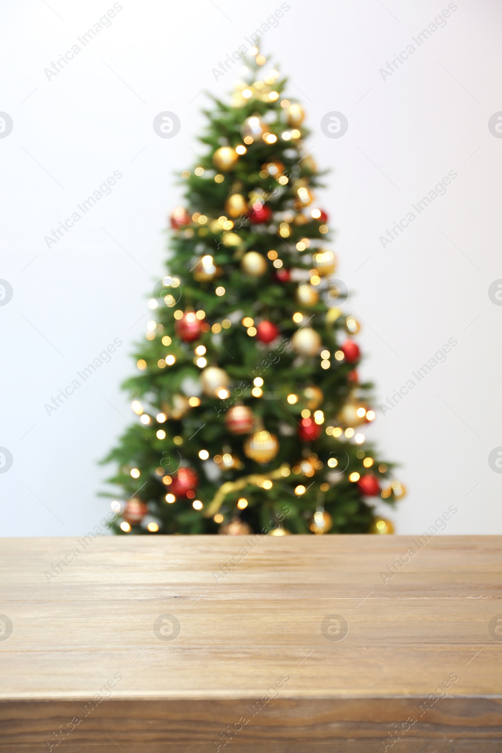 Photo of Wooden table and blurred Christmas tree with fairy lights on background