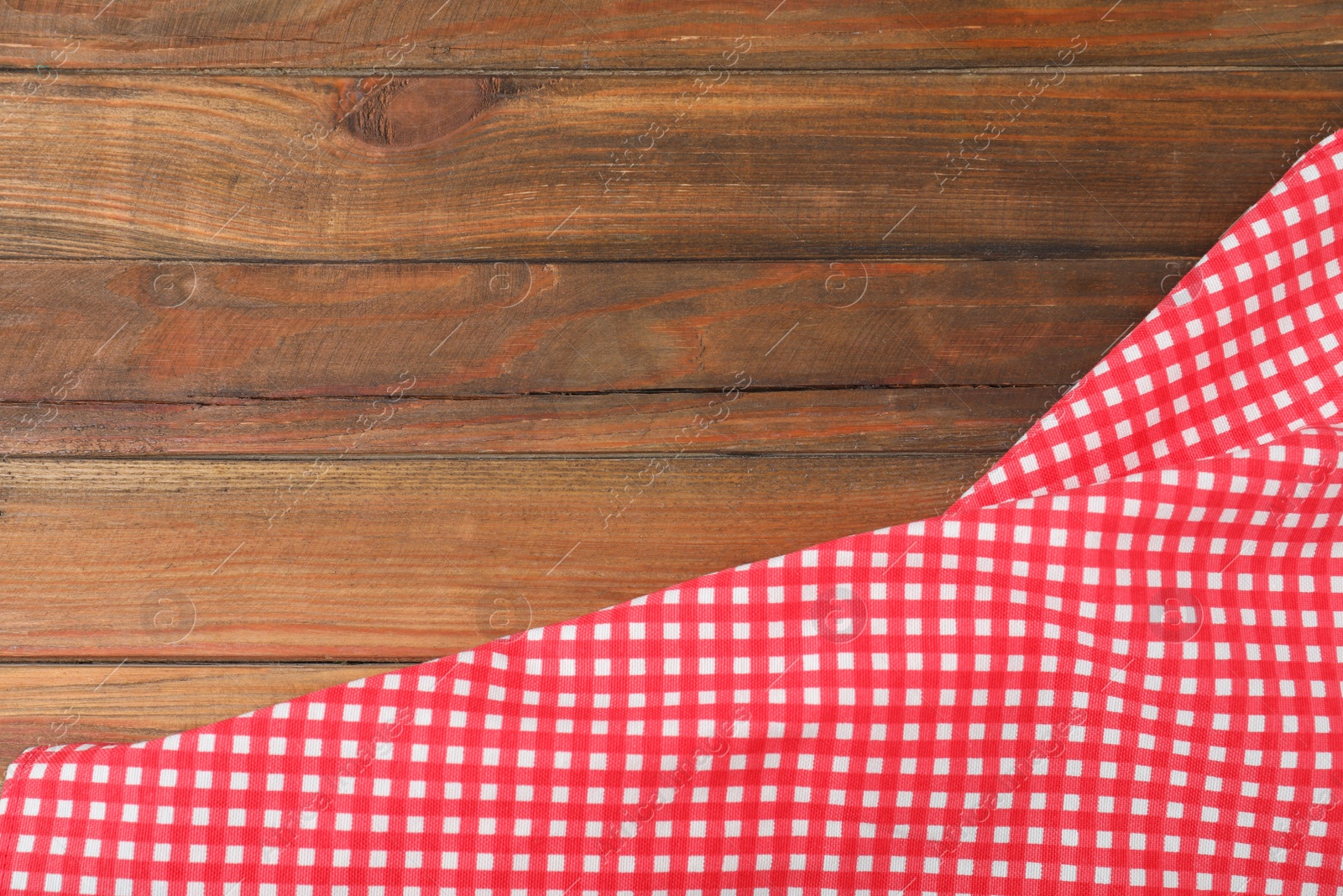 Photo of Checkered picnic blanket on wooden background, top view. Space for text