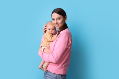 Photo of Happy mother with her cute baby on light blue background