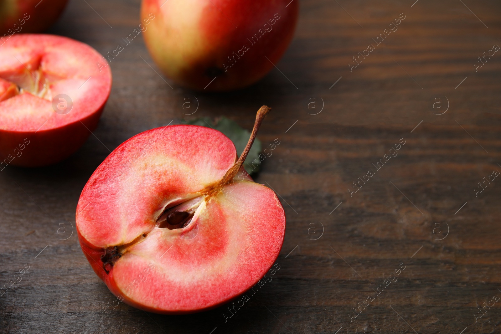 Photo of Tasty apples with red pulp on wooden table, closeup. Space for text