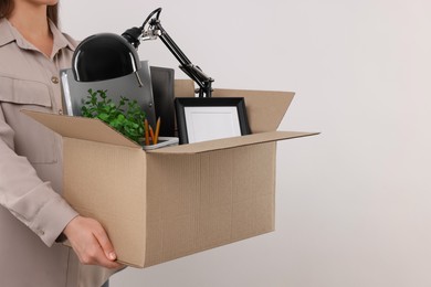 Photo of Unemployed woman holding box with personal office belongings on white background, closeup. Space for text