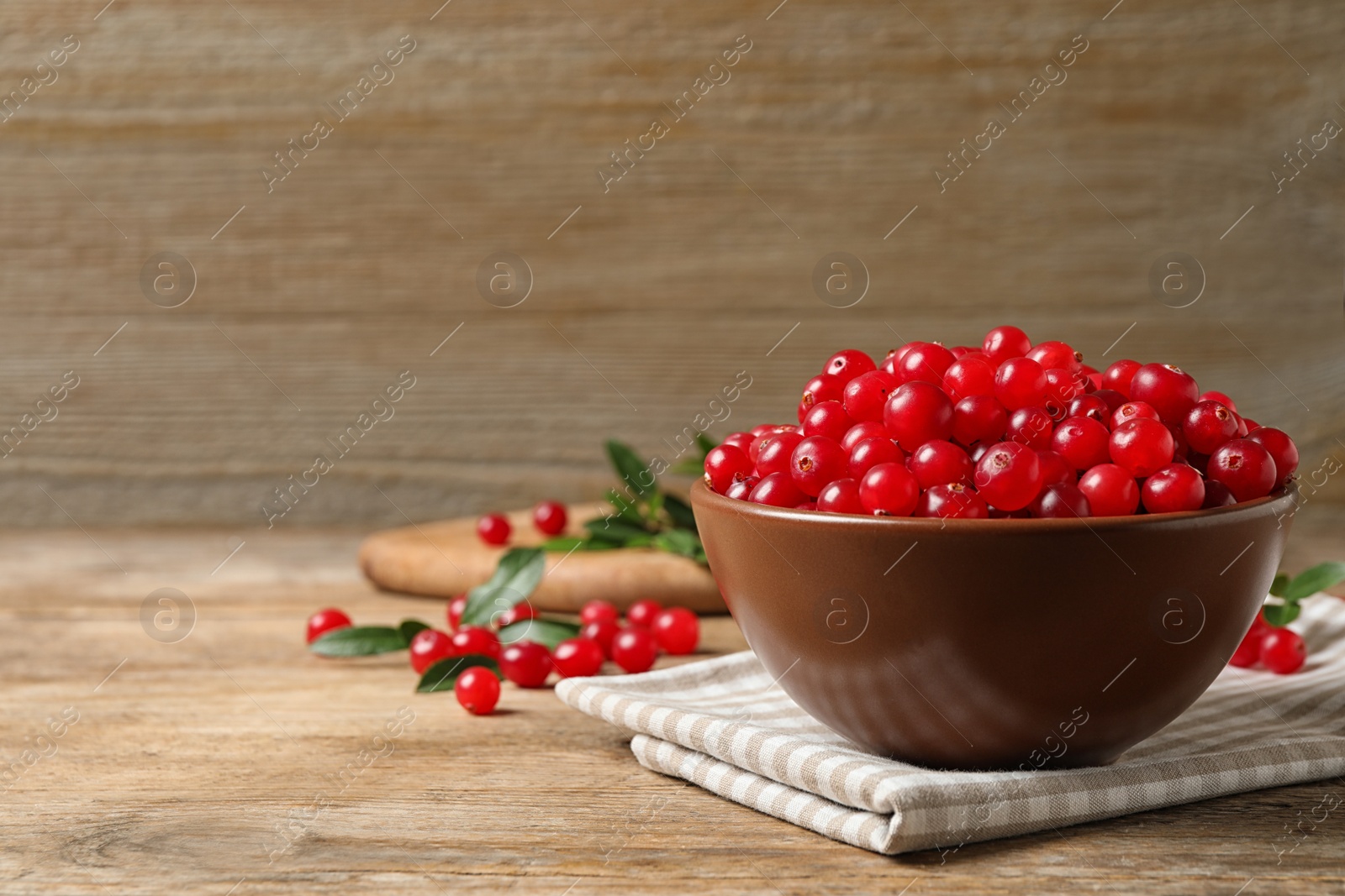 Photo of Tasty ripe cranberries on wooden table, closeup. Space for text