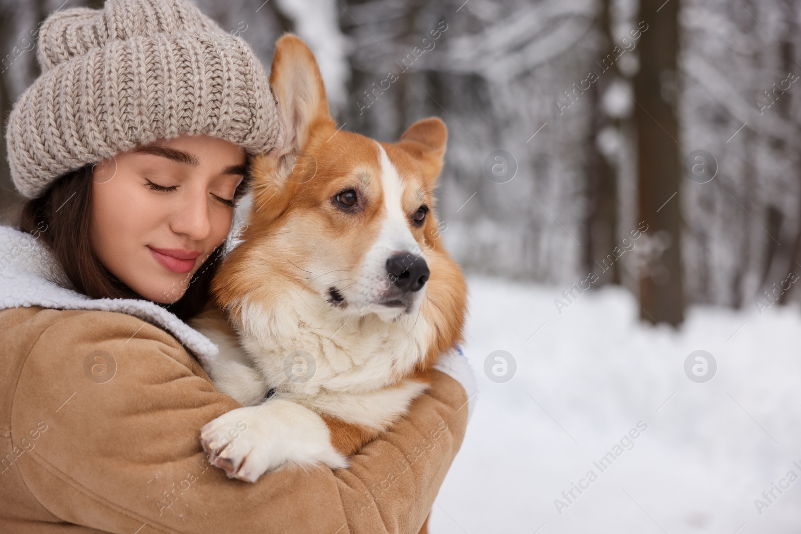 Photo of Woman with adorable Pembroke Welsh Corgi dog in snowy park, space for text