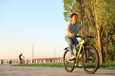 Handsome young man riding bicycle on city waterfront