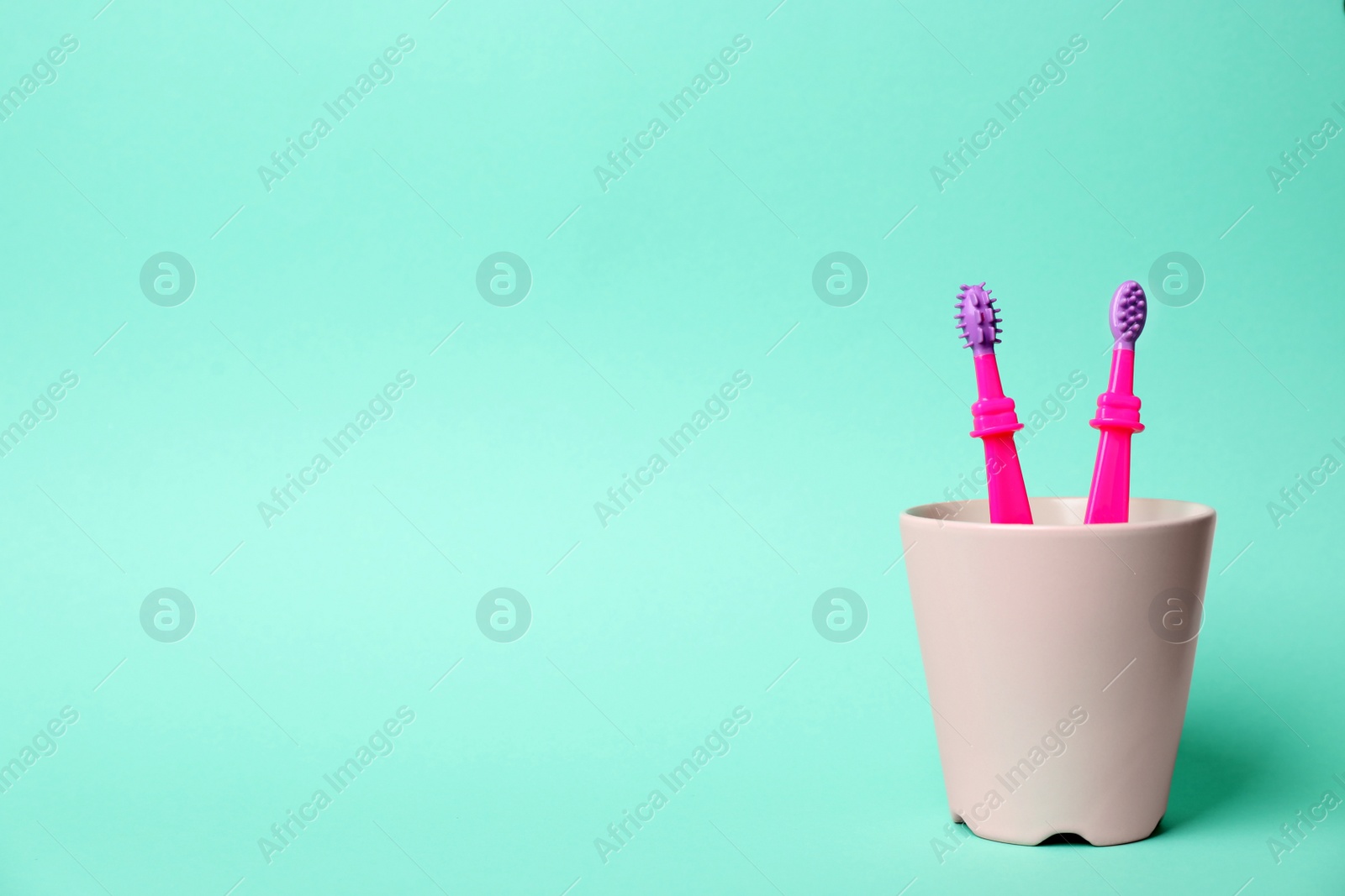 Photo of Baby toothbrushes in holder and space for text on color background