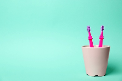 Baby toothbrushes in holder and space for text on color background