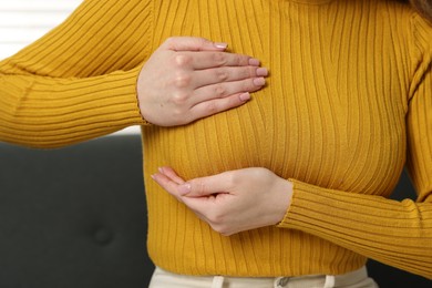 Mammology. Young woman doing breast self-examination at home, closeup