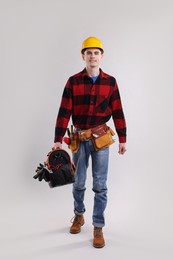 Professional repairman with tool box on light grey background