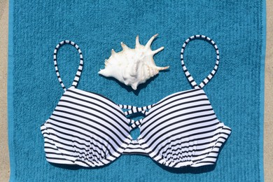 Blue beach towel, seashell and swimsuit on sand, top view