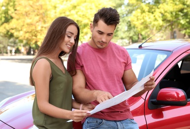Photo of Happy young couple with map near car outdoors