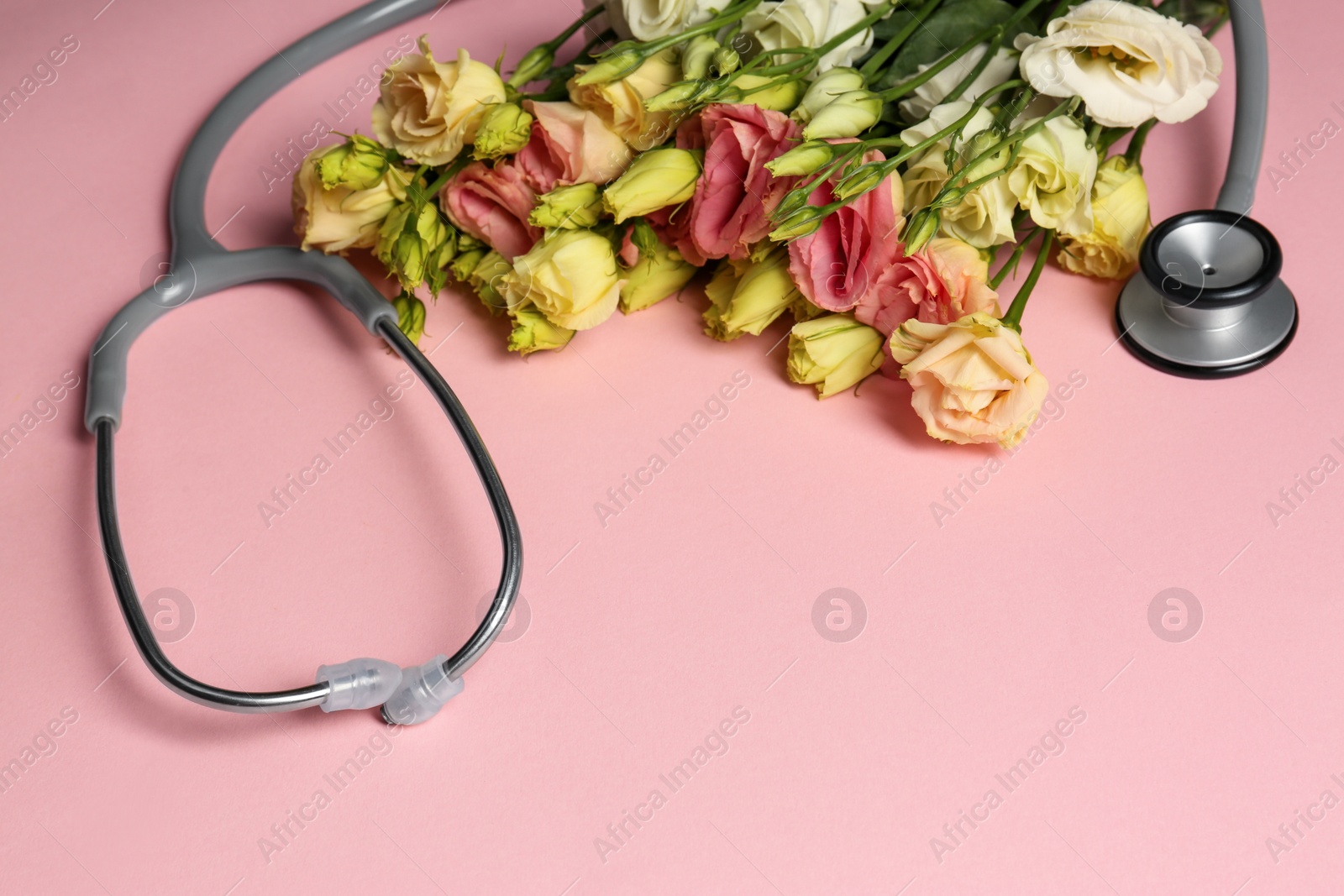 Photo of Stethoscope and flowers on pink background. Happy Doctor's Day