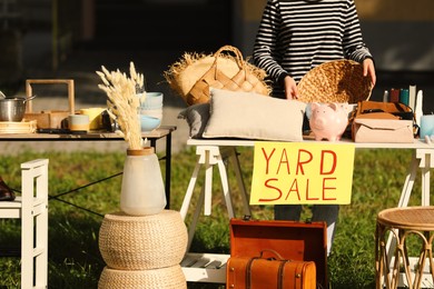 Photo of Woman near tables with different stuff on garage sale in yard