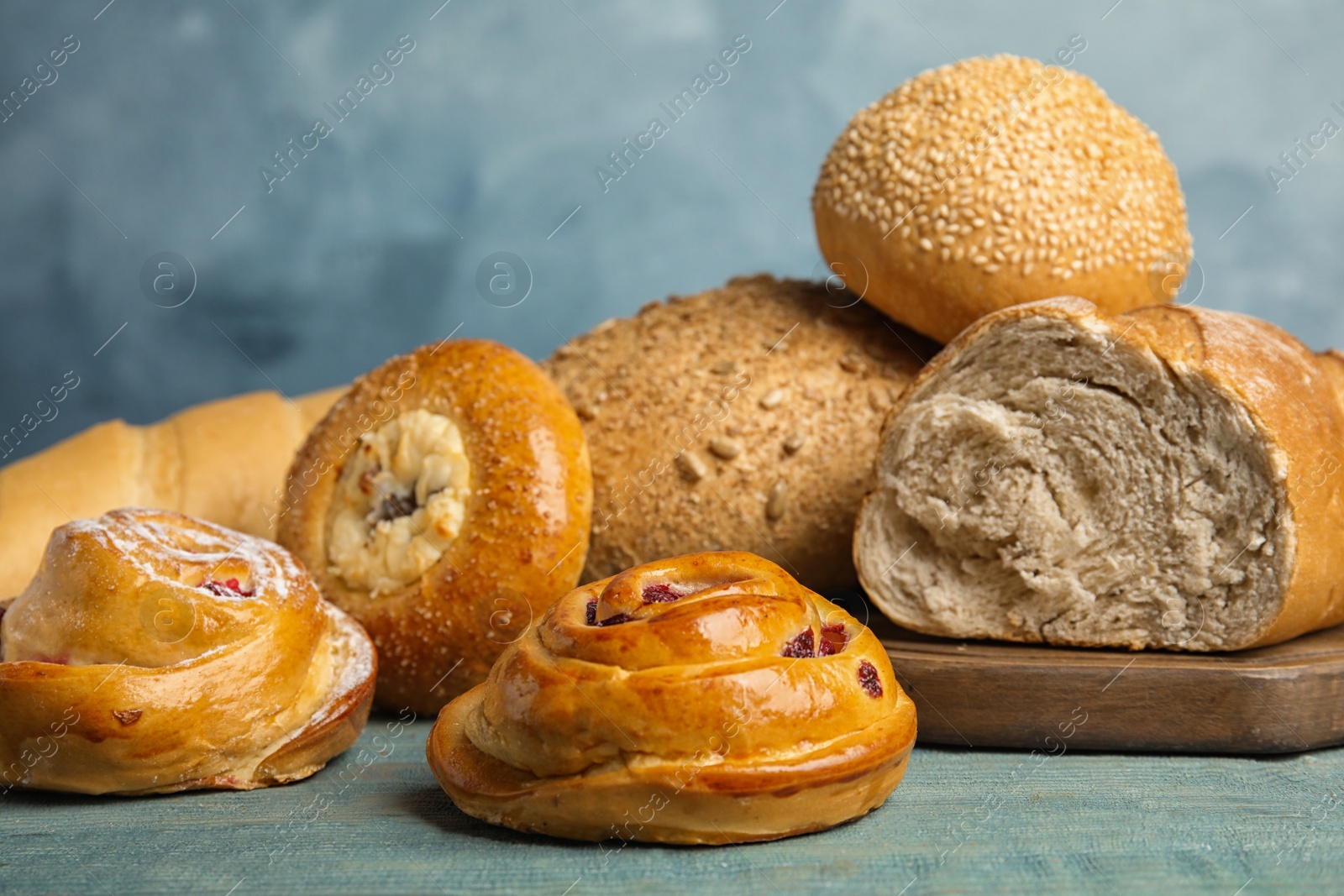 Photo of Fresh breads and pastries on blue wooden table