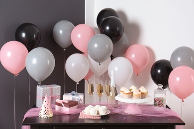 Photo of Party treats and items on table in room decorated with balloons