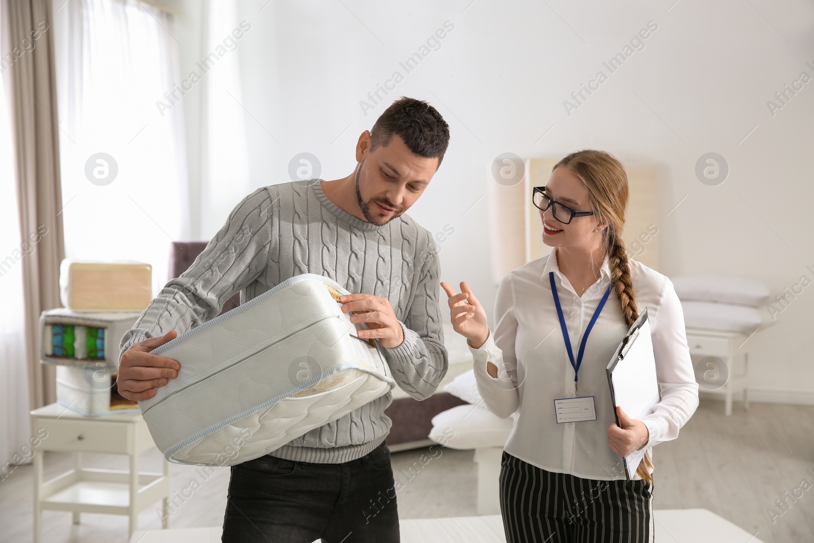 Photo of Young saleswoman consulting man in mattress store