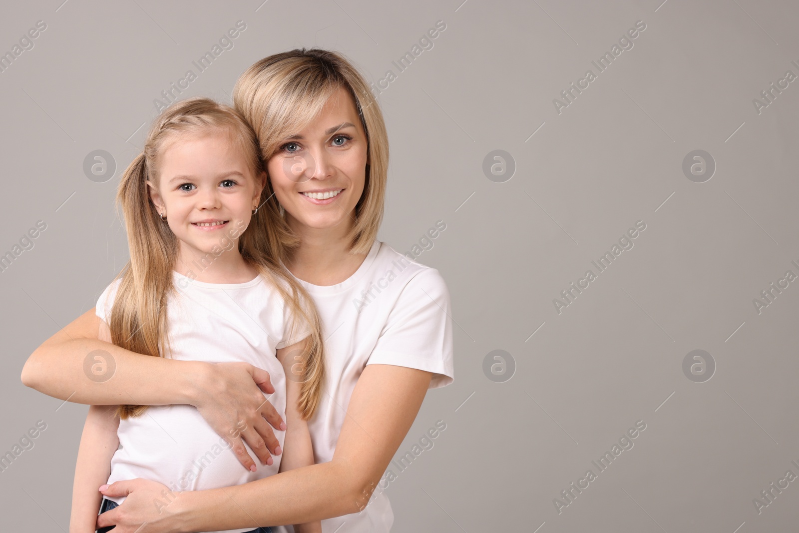 Photo of Family portrait of happy mother and daughter on grey background. Space for text